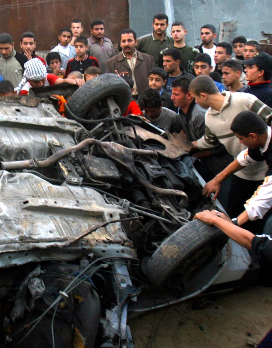 Palestinians gather around the wreckage of a car that was hit by an Israeli missile in Gaza City on Wednesday.
