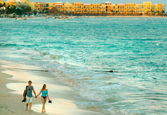 A couple of tourists walk on the beach at sunset Dec. 14, 2005, in Playa del Carmen, south of Cancun, Mexico.