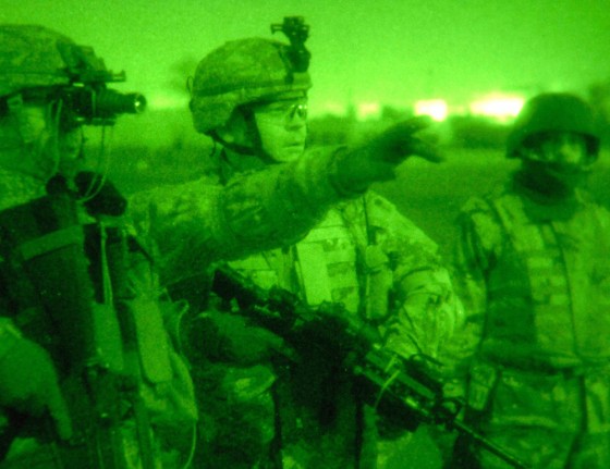 US Army officer Maj. Engen gestures beside Capt. Fournier and an Iraqi army officer during a raid in Baiji