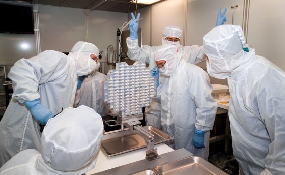 The Stardust mission's top scientist, Donald Brownlee of the University of Washington, flashes victory signs for the successful arrival of Stardust material at NASA's Johnson Space Center. The comet dust is contained in the grid at center.