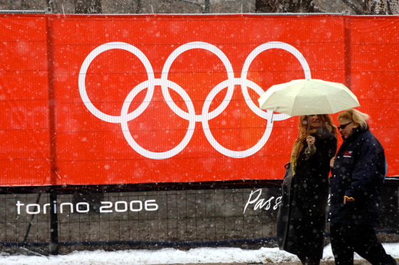 Pedestrians walk under a light snowfall in Turin, northern Italy, Thursday. Heavier snow was falling in the nearby mountains.
