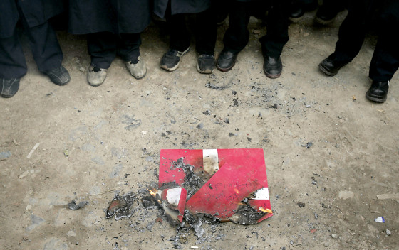 Iranian students stands next to a burnt