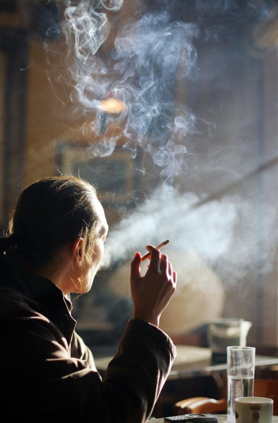 A woman smokes a cigarette and drinks a
