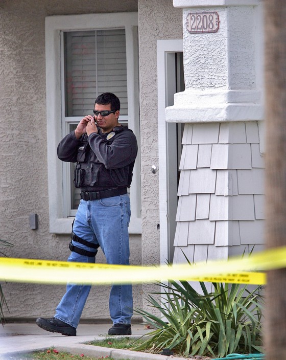A police officer stands outside a house in Mesa, Ariz., where five people were found dead Tuesday.