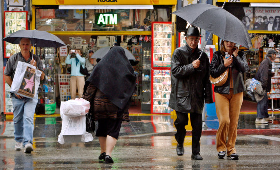 Pedestrians cross a wet Hollywood Blvd. on Monday.