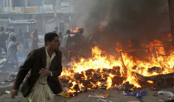 Man runs past burning debris at market after series of bomb attacks in Baghdad's Sad'r city