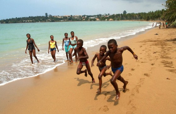 Children run on the beach as people look on at Sao Tome, Sao Tome and Principe, July, 18, 2005. The tranquil scene is one of many to be had in palm-fringed Sao Tome and Principe, a remote pair of volcanic islands smack dab on the equator whose attraction lies in what this undeveloped corner of the world lacks: No mass tourism. No traffic. No terrorism.