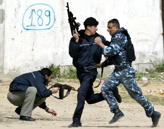 Palestinian police officers, one injured, take cover Monday during a gunbattle with Palestinian gunmen on the road leading to the Erez crossing between the Gaza Strip and Israel.