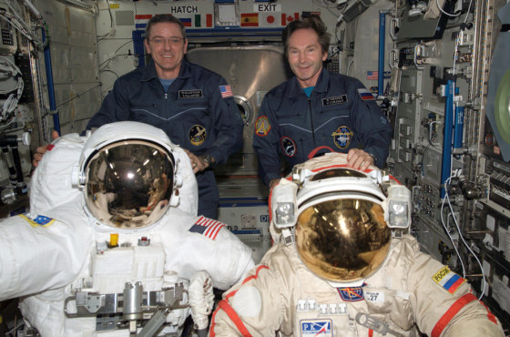 Station commander Bill McArthur and Russian cosmonaut Valery Tokarev stand behind NASA and Russian suits for spacewalks. For a time, equipment concerns left the station in a "no-go" condition for spacewalks, but NASA has come up with a contingency plan.