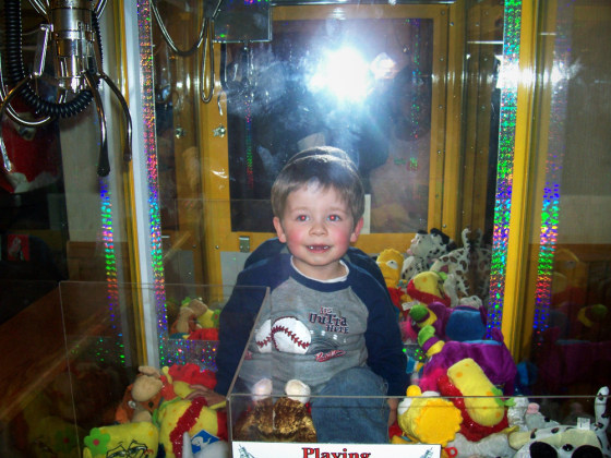 Devin Haskin, 3, plays inside the Toy Chest claw machine at Godfather's Pizza on Sunday in Austin, Minn., after crawling through the toy discharge chute.