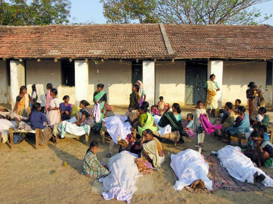 Relatives sit besides the dead bodies of those killed in a Maoist attack in Dharbaguda