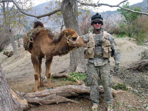 A U.S. Army soldier meets an inhabitant of Jauro, an Afghan village, used to carry firewood cut from local trees down steep hills, on Tuesday.