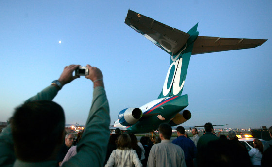 An employee takes a picture as the last Boeing 717 is towed the the flight ramp Thursday in Long Beach, Calif. It was the last commercial passenger jet to the built in California.