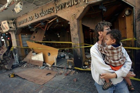 A tourist holds her son as she walks Tuesday past a store hit by one of the bombings Monday at the Sinai seaside city of Dahab, Egypt.