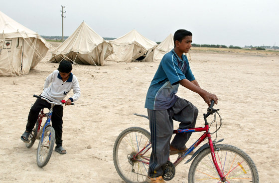 Iraqi boys ride bicycles in a camp in Ba
