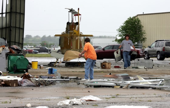 Bob Tharp, left, and Billy Tharp clean up after high winds blew the doors off an airplane hanger at an airport in Gainesville, Texas, on Saturday.
