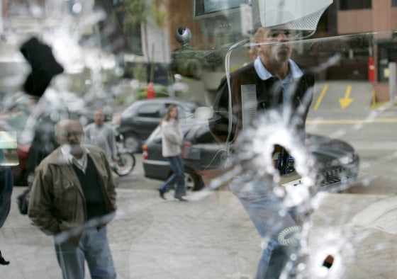 Pedestrians observe an office building shot at by gangsters in Sao Paulo