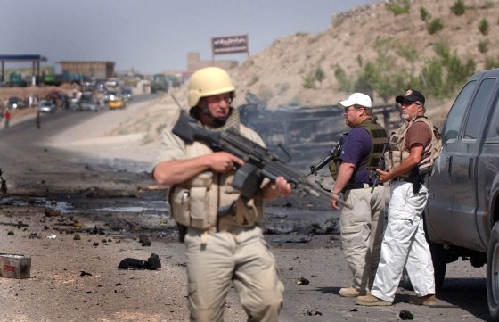 Foreign security guards stand near the scene of a car bomb explosion in Herat on Thursday. 