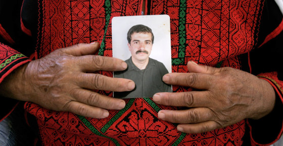 The mother of the Hamas commander Ibrahim Hamed holds his portrait at the family house in the West Bank village of Silwad near Ramallah on Tuesday.