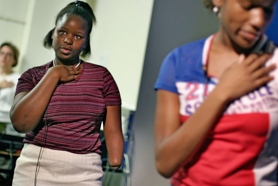 Damba Koroma, who made a video about her life as a victim of rebels in Sierra Leone, and Kamika Jones, 14, right, recite the Pledge of Allegiance during their daily TV broadcast at Hammond Middle School, in Alexandria, Va.