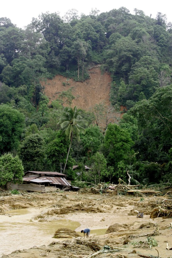 A Thai villager washes his hands in the stream created by a flash flood near his partly destroyed house in Uttaradit province, northern Thailand, on Wednesday.