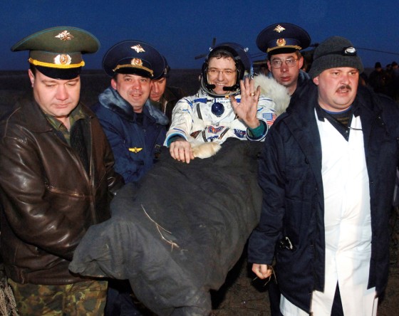 Astronaut Bill McArthur waves to the welcoming crowd gathered on the steppes of Kazakhstan as he is carried from the Soyuz craft that brought him and his crewmates back from the international space station in April. Astronauts returning from the station are carried because they're unaccustomed to gravity's effect.