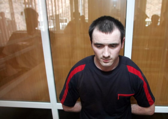 Nur-Pashi Kulayev listens in a plastic cage at a court room in Vladikavkaz, Russia, on Wednesday, as a judge lists weapons used by militants and federal troops in the deadly Beslan school hostage-taking.