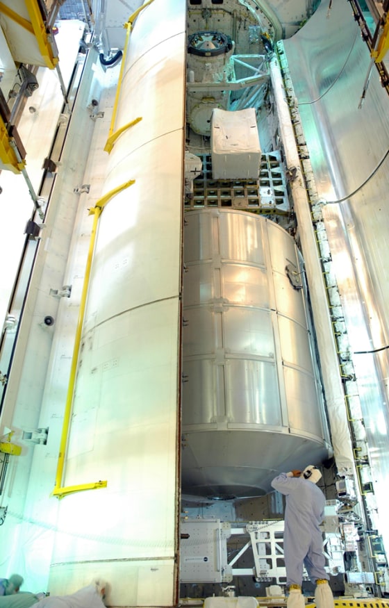 Workers close the payload bay doors on the shuttle Discovery at Kennedy Space Center's Launch Pad 39B in Florida on Monday. Inside the payload bay can be seen the Leonardo cargo module, at bottom, and the shuttle's integrated cargo carrier above it. NASA has given the go-ahead for Discovery's launch next month, even though the agency's top safety official and chief engineer voted against the plan.