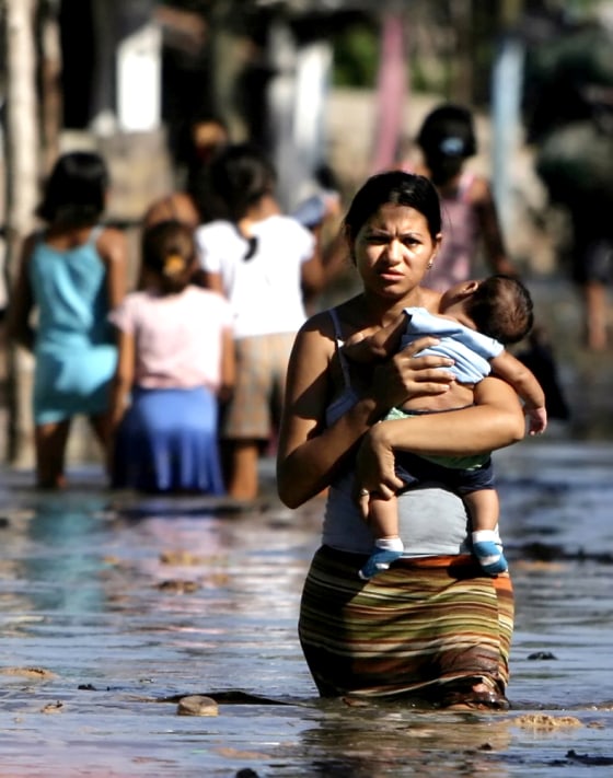 A woman walks with her son through floodwaters in Cedeno, Honduras, on Tuesday. Waves damaged at least 300 houses in the nation, officials said.
