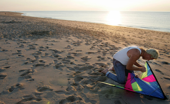 A man prepares his kite for flight just before sunset on the beach at the Cape Cod National Seashore.