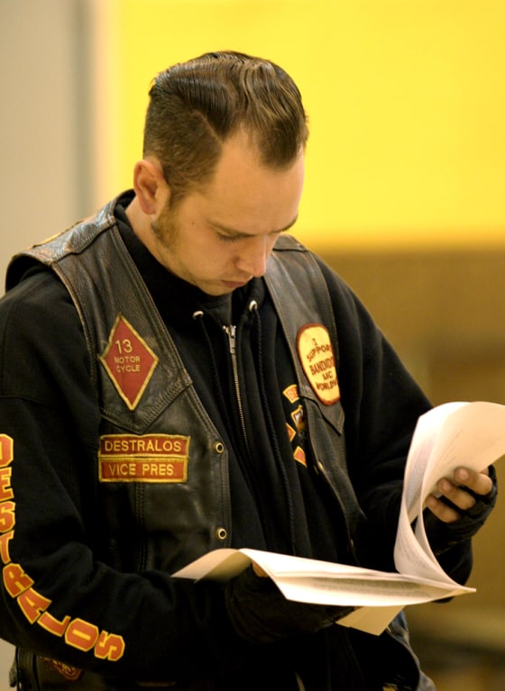 A man reads the report on the shootings at Monday’s community meeting.