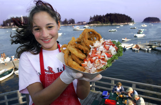 Lesley Spencer of Malvern, Pa., holds up a lobster roll and onion rings at Five Island Seafood in Five Islands, Maine, July 16, 2006. 
