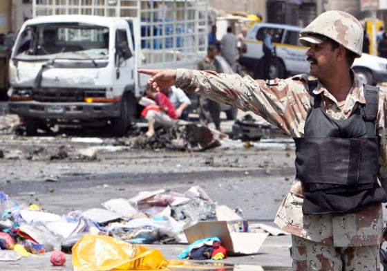 An Iraqi soldier gestures as he secures the site of a car bomb attack in which one man was killed and 15 wounded in central Baghdad