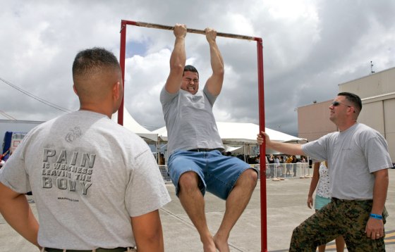 Matt Elam, center, competes in a pull-up contest while Marine recruiters Sgt. Marco Hartanto, left, and Gysgt. Brian Lancioni look on at Marine Corps Base Hawaii on July 4 in Kaneohe, Hawaii.