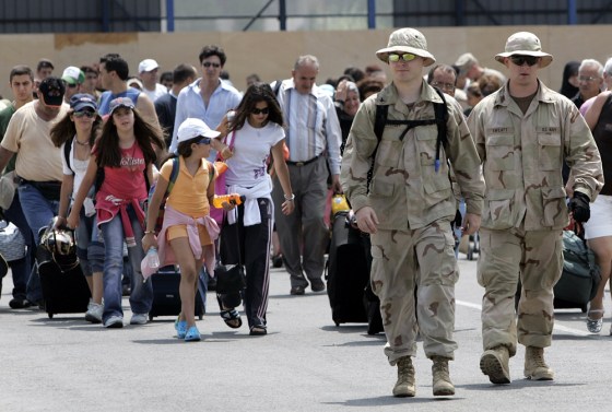 Two US sailors lead American citizens to the USS Trenton, which will evacuate them to Cyprus.