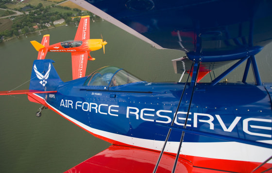In this photograph provided by Rock*Rho Publishing, aerobatic air show pilot Ed "Hamster" Hamill flies in formation with fellow air show performer Dave Martin, background, over Lake Winnebago during the EAA AirVenture in Oshkosh, Wis.