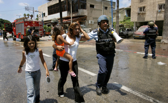 An Israeli policeman escorts a woman and children after a rocket exploded in Haifa on Tuesday.