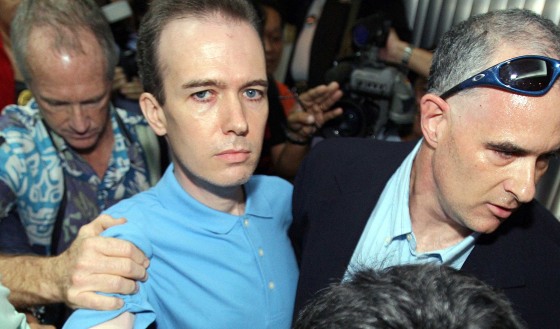 Unidentified U.S. officials escort US teacher John Mark Karr at the Thai Immigration Department in Bangkok, August 17, 2006. 