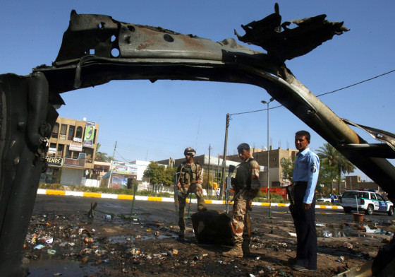 Iraqi soldiers view the wreckage of a car bomb that detonated near a&nbsp;police patrol in Baghdad on&nbsp;Thursday.