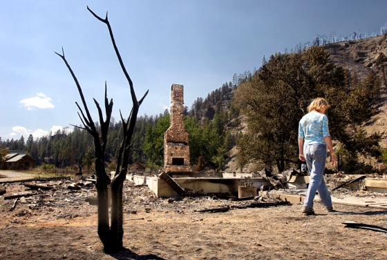 Mina Cox walks through the remains of her burned-out home Friday near Absarokee, Mont. The 180,000-acre Derby Mountain fire ripped through the area and burned Cox's home but left the guest house at far left untouched.