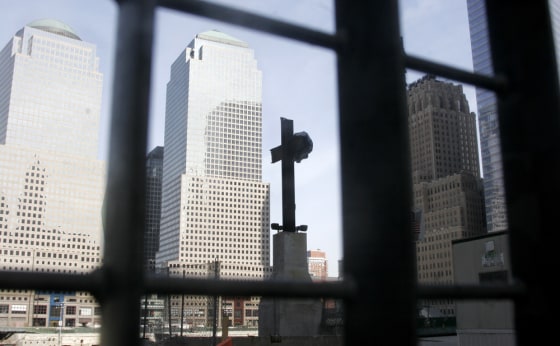 A cross formed by beams from the original World Trade Center is visible through a fence surrounding the World Trade Center site in New York. 
