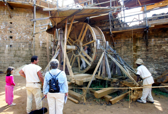 Tourists watch workers man a wooden spinning wheel, activating a pulley system to lift a load of stones atop a tower, at the Guedelon castle construction site, in a forest in Burgundy, 125 miles south of Paris, Aug. 1. 