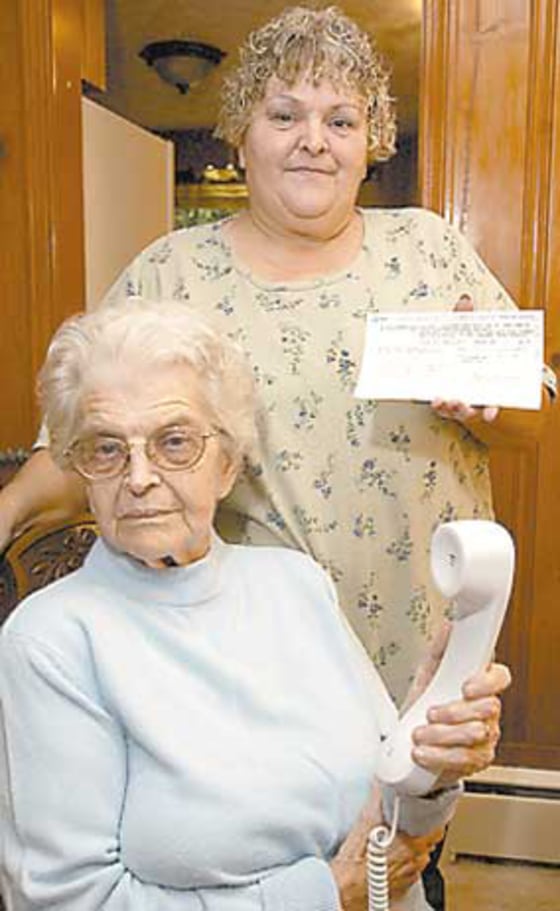 Cinda Howell stands behind her mother, Ester Strogen, holding a phone bill. Howell and other family members were upset when they found out Ester Strogen had been leasing rotary dial telephones for the past 42 years from AT&T.