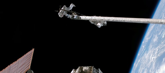 Spacewalkers Piers Sellers and Michael Fossum hang on an orbital inspection boom during Discovery's mission in July. Sellers accidentally lost a spatula that is now orbiting Earth and is due to burn up next month.