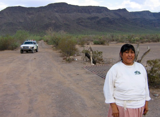 Ofelia Rivas, an Indian activist from the Tohono O'odham tribe, stands by a traditional crossing into Mexico that will be closed under a plan pushed by the Border Patrol. A Border Patrol vehicle, in the background, tracks her whenever she comes to this village.