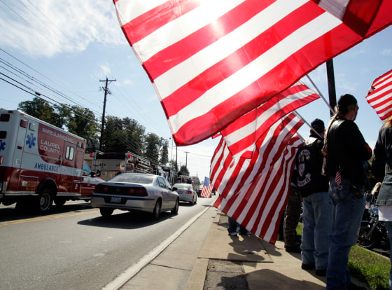 Rob Duff, of Corbin, Ky. far right, holds an American flag in front of the London Funeral Home where services were being held for Sgt. 1st Class Charles Jason Jones in London, Ky., on Saturday.