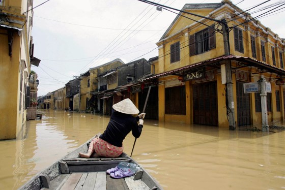 A woman powers her boat at a flooded str