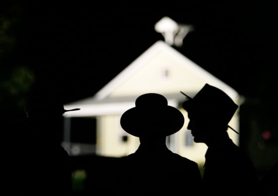 Amish men are seen in front of the schoolhouse where a gunman shot several students and himself in Nickel Mines, Pa., on Monday.