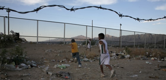 Mexican children run toward the border to the United States in Rancho Anapra outside of Ciudad Juarez, Mexico, on May 12. New Mexico is right on the other side of the fence. About a 100 yards away the fence stops abruptly and on the other side is a flat field where the children often play soccer.