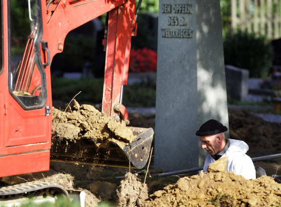 Workers examine a mass grave on the churchyard in Menden